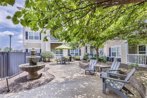 a courtyard with a fountain and benches in front of a building at Aventura at Forest Park, St. Louis