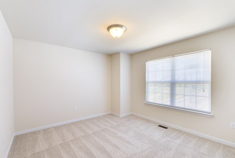 an empty living room with a large window and carpeting