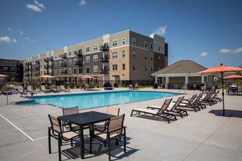a swimming pool with tables and chairs in front of a building