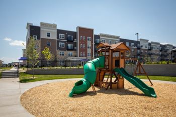 a playground with a green slide in front of an apartment building