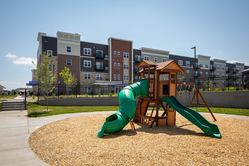 a playground with a slide in front of an apartment building  at The Edison at Woodbury, Woodbury, 55129