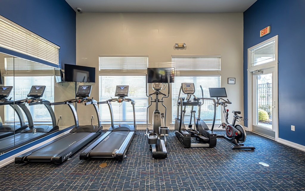 A gym with treadmills, elliptical machines, and stationary bikes.