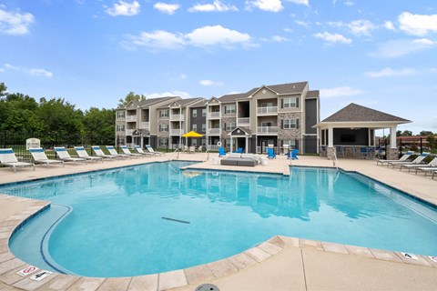 A large swimming pool in front of a multi-story apartment building.