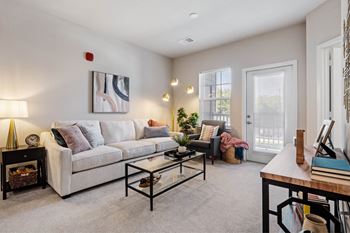 A living room with a white couch, a coffee table, and a painting on the wall at Aventura at Wentzville I & II Apartments, Missouri, 63385