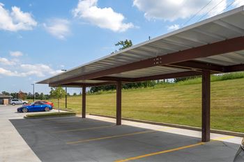 A blue car is parked in a parking lot under a covered structure at Aventura at Wentzville I & II Apartments, Wentzville