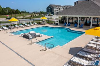 A large swimming pool surrounded by sun loungers and umbrellas at Aventura at Wentzville I & II Apartments, Missouri, 63385