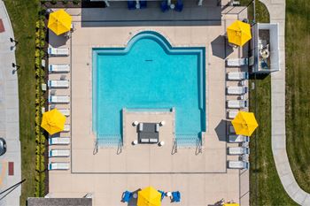 A large rectangular pool surrounded by yellow umbrellas and lounge chairs at Aventura at Wentzville I & II Apartments, Wentzville, MO