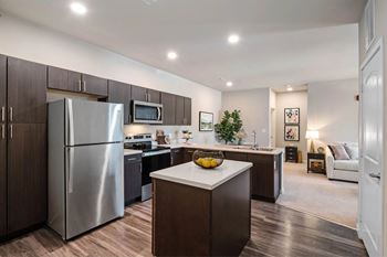A modern kitchen with a refrigerator, microwave, and oven at Aventura at Wentzville I & II Apartments, Wentzville, Missouri