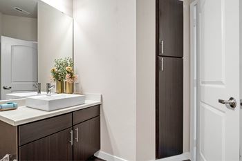 A bathroom with a sink, mirror, and brown cabinets at Aventura at Wentzville I & II Apartments, Wentzville, MO, 63385