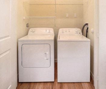 Two white front loading washing machines in a small laundry room at Aventura at Wentzville I & II Apartments, Missouri, 63385