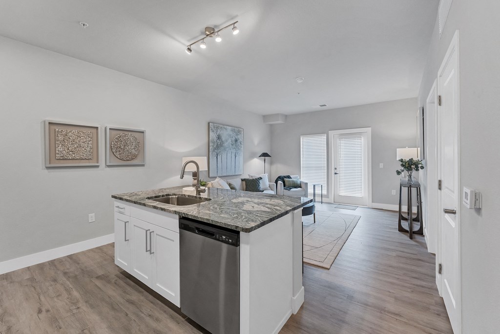 a kitchen with an island and a living room in the background  at The Edison at Chapel Hills, Colorado