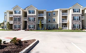 A large apartment complex with multiple buildings and a parking lot in front.