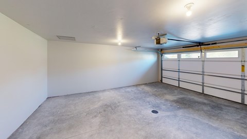 A spacious garage with a concrete floor and a white wall.