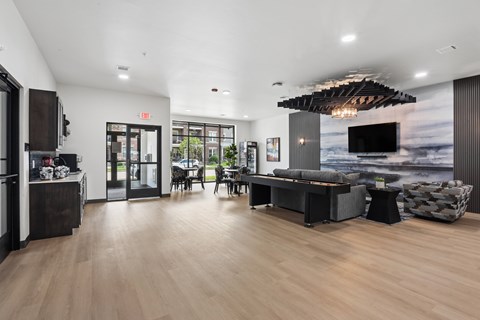 A modern living room with a wooden floor and a large TV mounted on the wall.