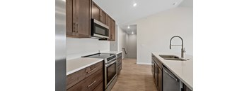 A modern kitchen with dark wood cabinets and stainless steel appliances.