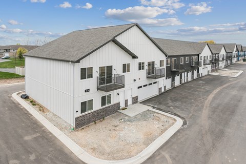 A white building with a grey roof is surrounded by other similar buildings.