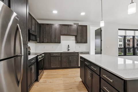 A modern kitchen with dark wood cabinets and stainless steel appliances.