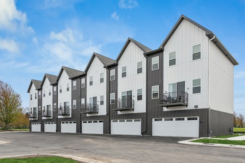 A row of modern townhouses with garages in front.