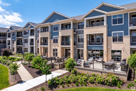 an exterior view of an apartment building with benches and landscaping