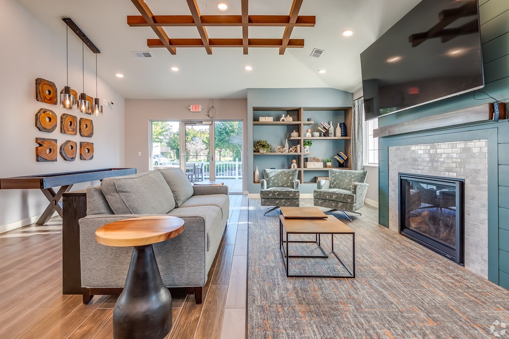 A modern living room with a grey couch, a wooden coffee table, and a fireplace.