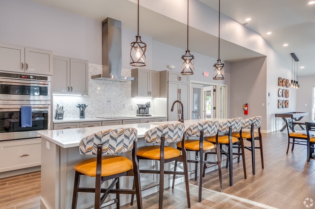 A kitchen with a white counter top and orange chairs.