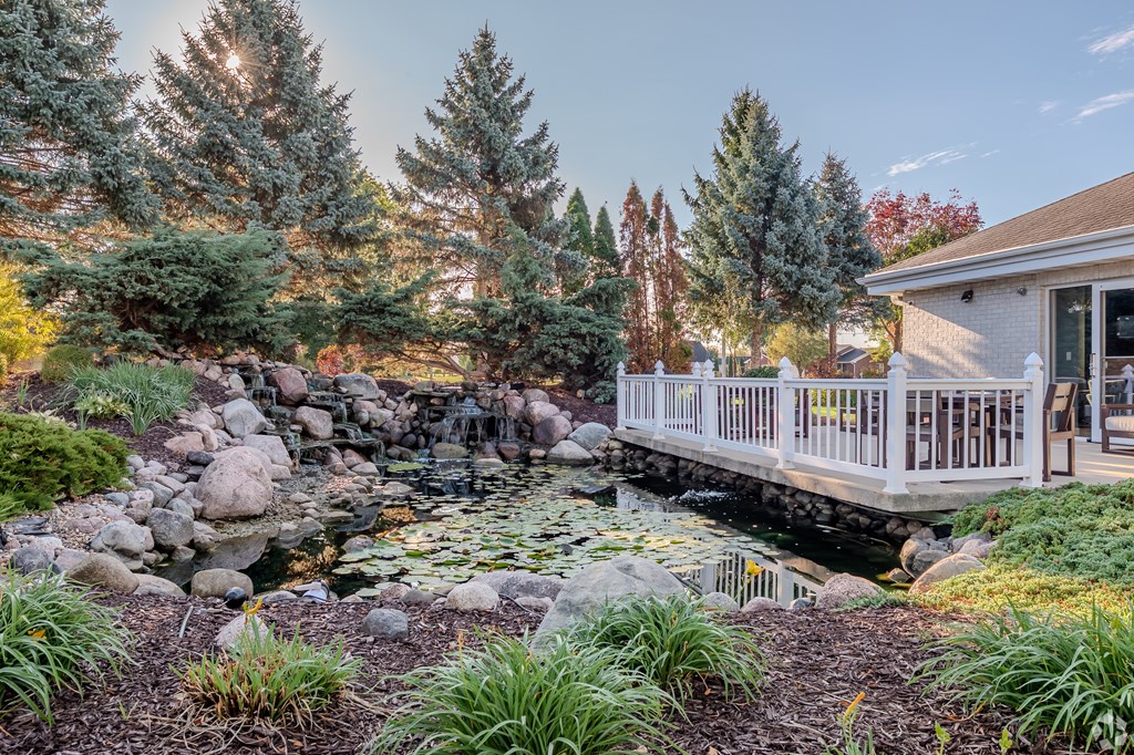 A pond with a rocky shore and a white deck in the background.