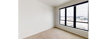 A room with a carpeted floor and a large window overlooking a parking lot.