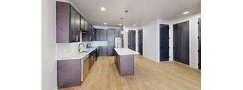 A modern kitchen with wooden floors and a central island.