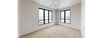 A room with two windows overlooking a beach.