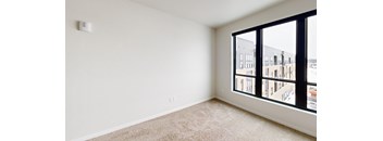 A room with a carpeted floor and a window overlooking a cityscape.