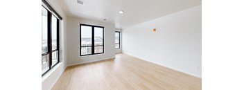 A large empty room with wooden floors and a window overlooking a balcony.
