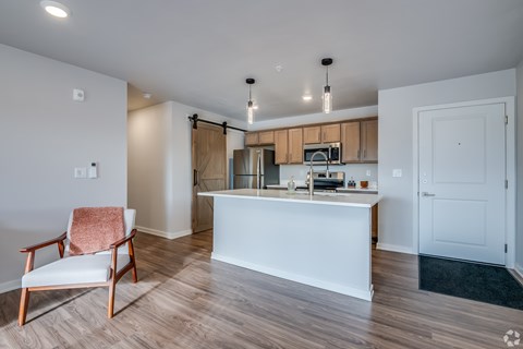 A kitchen with a white island and a chair with a pink towel on it.