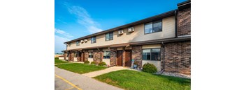 the front of a brick apartment building with a sidewalk and grass
