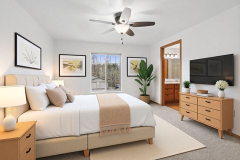 A bedroom with a large bed, a ceiling fan, and a window with a view of trees.