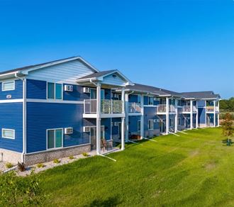 a row of blue condominiums with a green lawn in front of them