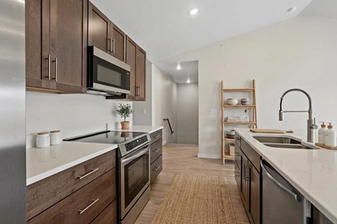 A modern kitchen with dark wood cabinets and stainless steel appliances.