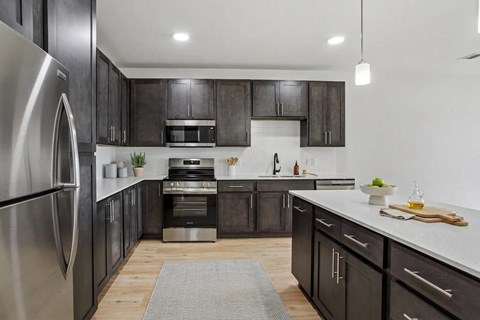 A modern kitchen with dark wood cabinets and stainless steel appliances.