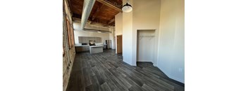 A room with a kitchen area and a dining table.