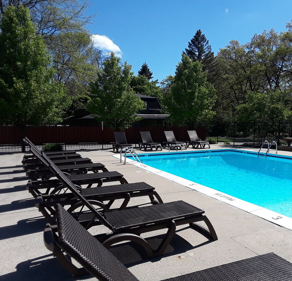 a swimming pool with chaise lounge chairs and trees in the background