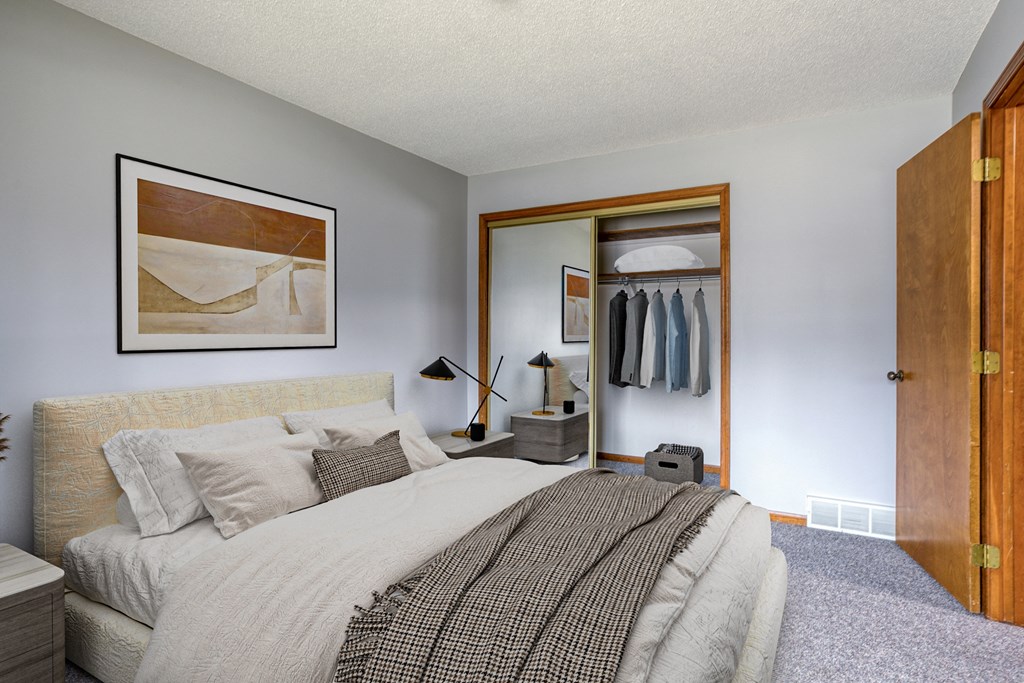 a bedroom with a large bed and a closet with clothes in it