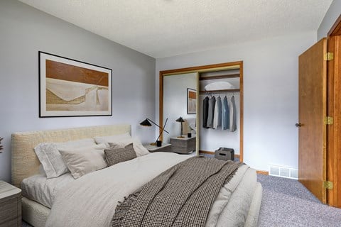 a bedroom with a large bed and a closet with clothes in it