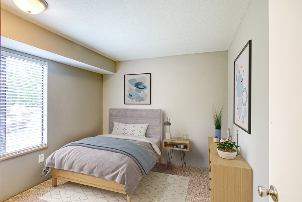 A bedroom with a bed, nightstand, and a plant on a dresser.