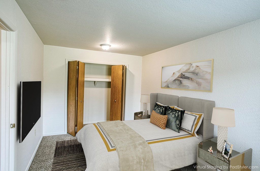 A bedroom with a bed, nightstand, and a painting on the wall.