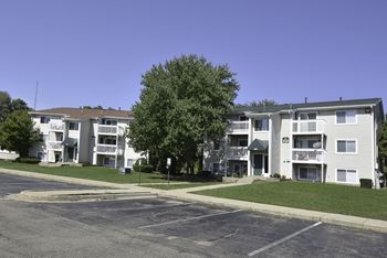 Apartment complex with a parking lot in front.