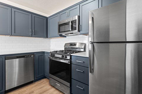 A modern kitchen with dark blue cabinets and stainless steel appliances.