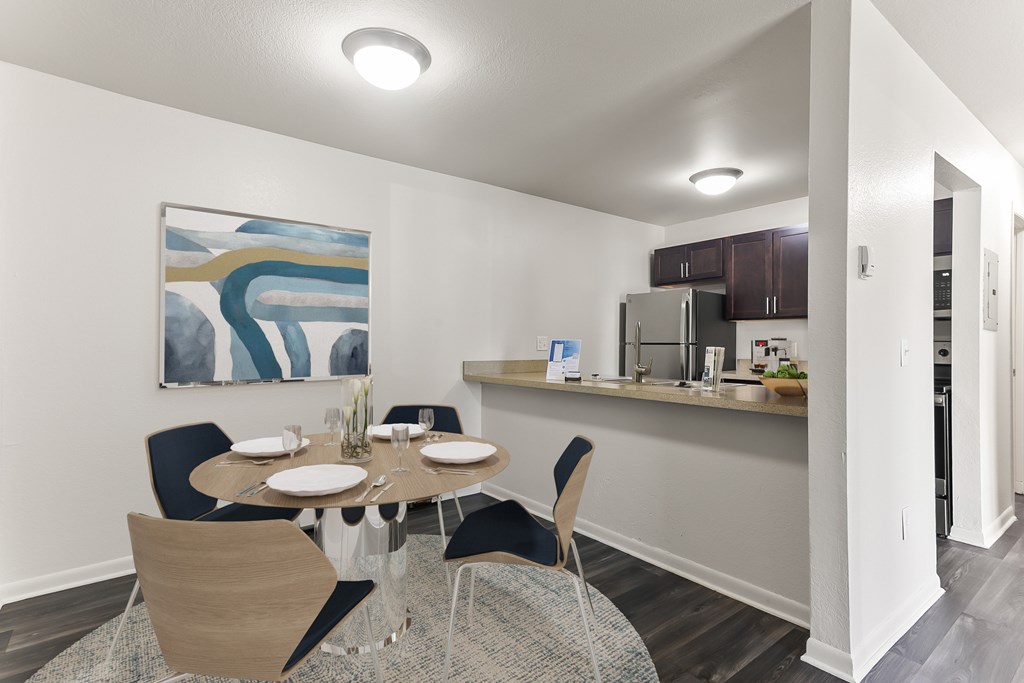 A dining room with a table set for two and a painting on the wall.