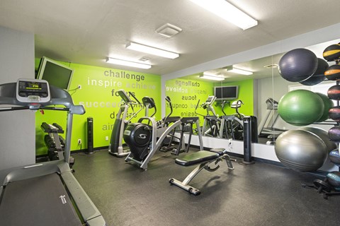 A gym with a green wall that says "challenge inspire succeed".