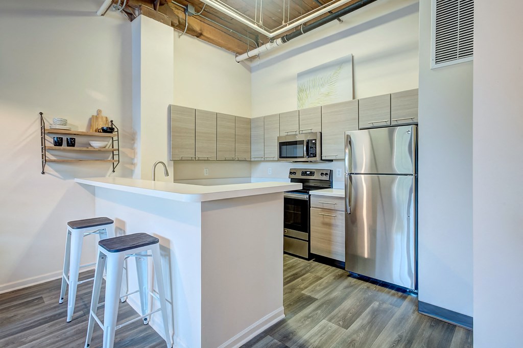 A kitchen with a white counter top and a stainless steel refrigerator.
