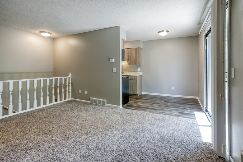 a living room with a staircase and a kitchen in the background