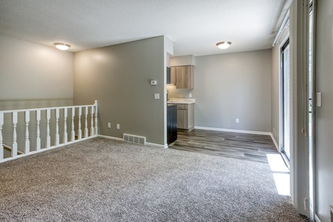 a living room with a staircase and a kitchen in the background